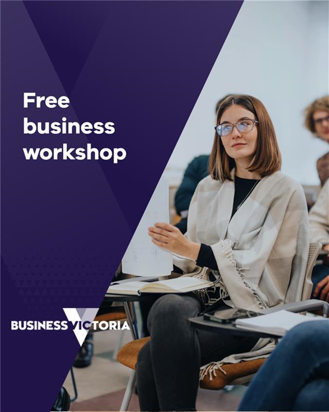 A person seated in a classroom setting holding a piece of paper, with notebooks and pens on the desk. The left side of the image features a purple banner with white text that reads “Free business workshop” and the Business Victoria logo at the bottom.